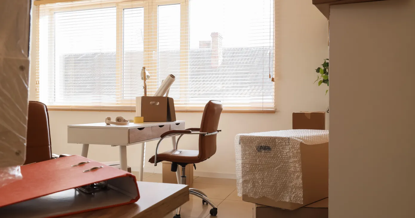 Office relocation and corporate downsizing, empty desk with cardboard moving boxes in a workspace during business transition or company office move