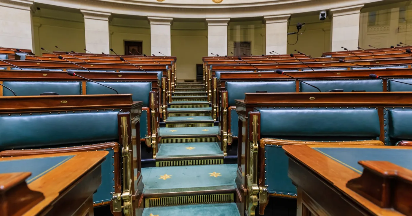 L’hémicycle de la Chambre des représentants, bancs bleus vides et pupitres de bois.